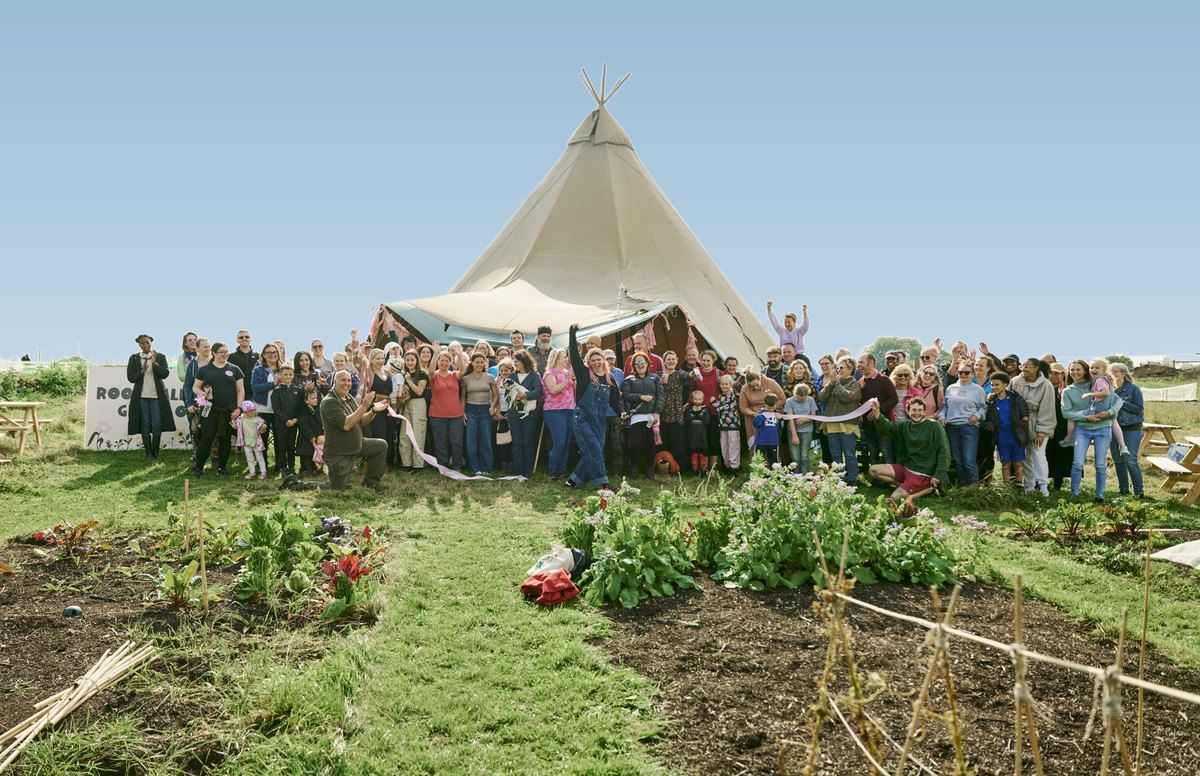 Members of a Roots growing community gathered in front of the tipi across the beds on an opening weekend